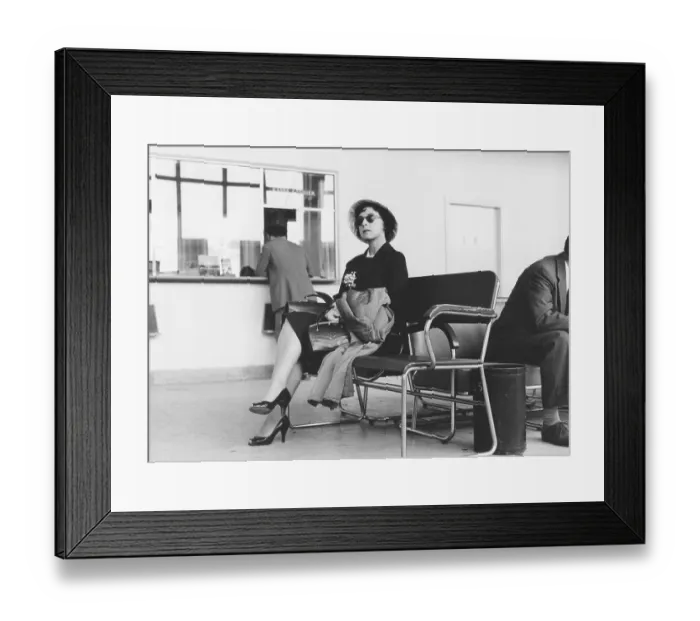Framed Print : In the 1950s. A woman in focus is sitting in the terminal building in Bromma airport Stockholm Sweden. She is waiting to depart with an airplane and sits on a bench and waits comfortable but ready, having her carry-on bag and handbag close