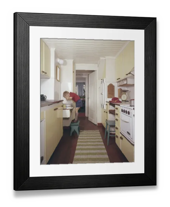 Framed Print : Kitchen of the 50s-60s. A boy is standing on a footstool and washes his hands and face