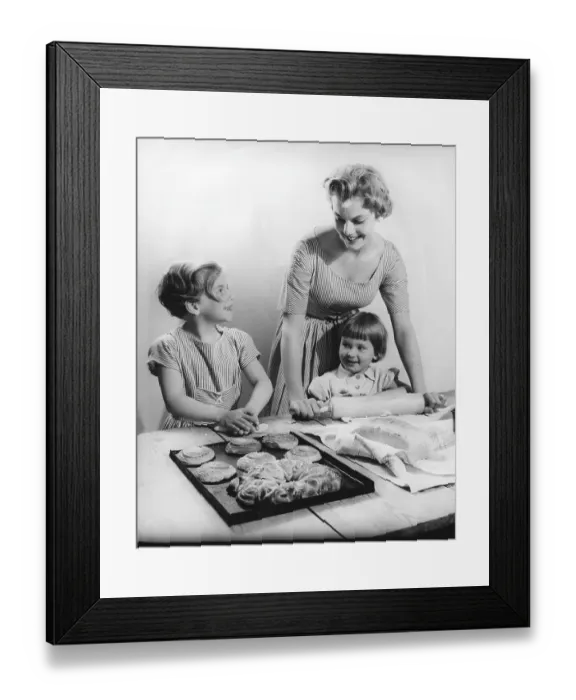 Framed Print : Baking in the 1950s. A mother with her children baking buns and bread together at a table Framed Print : Baking in the 1950s. A mother with her children baking buns and bread together at a table