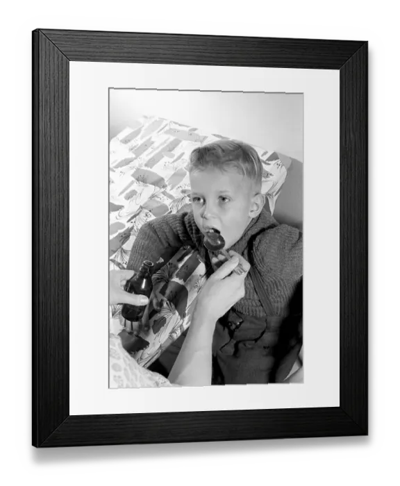 Framed Print : A boy is sick and won't take his medicine. His mother holds out a spoon and waits for him to gape and take it, and he does. He opens his mouth and takes it even though it for sure does not tase so good. Sweden 1956