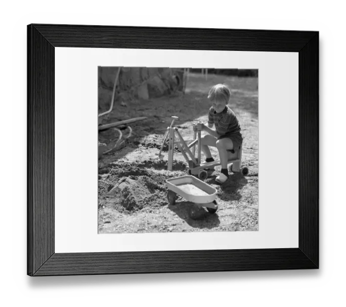 Framed Print : In the 1960s. A boy is playing with a toy excavator