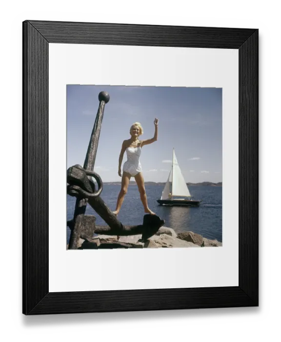 Framed Print : In the 1960s. A young blonde swedish girl in a typical 1960s bathing suit waves at someone behind the photographer
