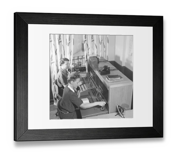 Framed Print : Telephony in the 1950s. Two women working at a telephone switchboard as it's operator
