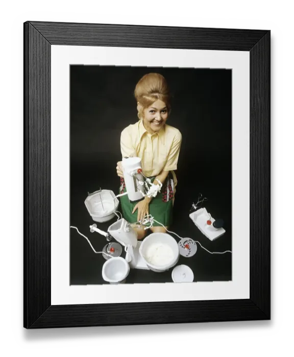 Framed Print : In the 1960s. A young woman pictured with an electric mixer having whipped cream Framed Print : In the 1960s. A young woman pictured with an electric mixer having whipped cream