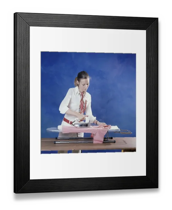 Framed Print : Ironing in the 1970s. A woman seen ironing her clothes