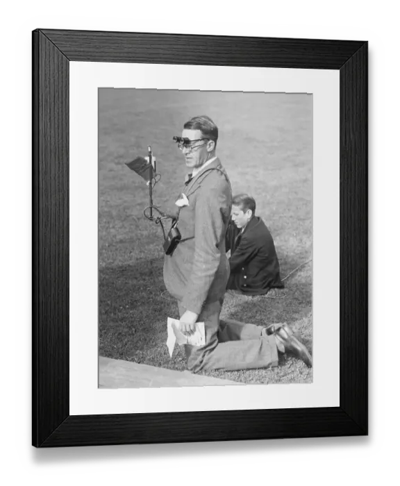 Framed Print : 1940s media man. A man is standing on his knees on the grass of the inner field of a sports stadium