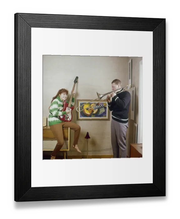Framed Print : In the 1960s. A couple is seen playing the trombone and an electric guitar Framed Print : In the 1960s. A couple is seen playing the trombone and an electric guitar