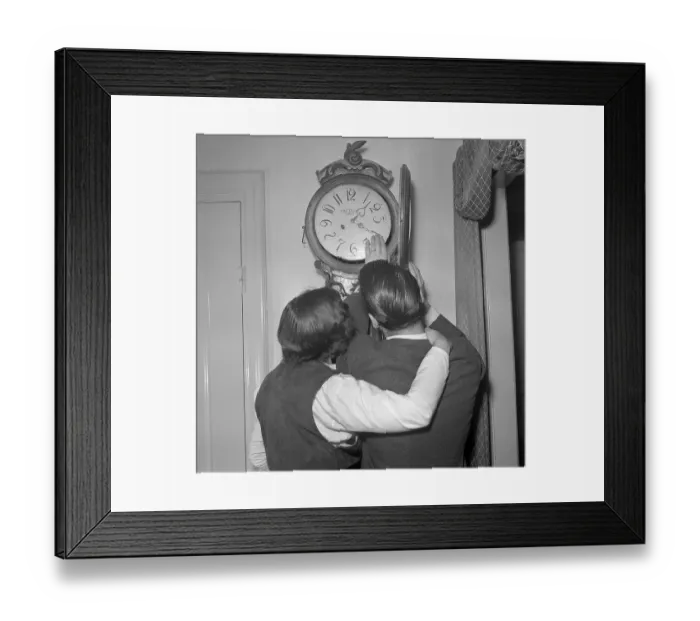 Framed Print : In the 1950s. A woman and a man in front of a antique clock with the clock-face visible