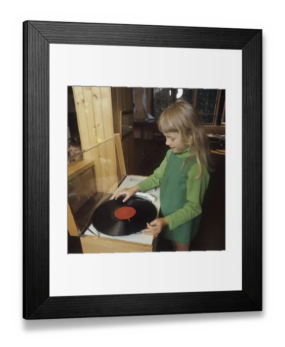Framed Print : A girl is standing at a gramophone that is going to play an LP with Klas Klaettermus