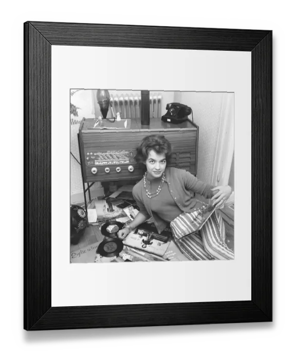 Framed Print : Radio listeners in the past. A woman is seen on the floor with records by popular singers and groups of the 1950s Framed Print : Radio listeners in the past. A woman is seen on the floor with records by popular singers and groups of the 1950s