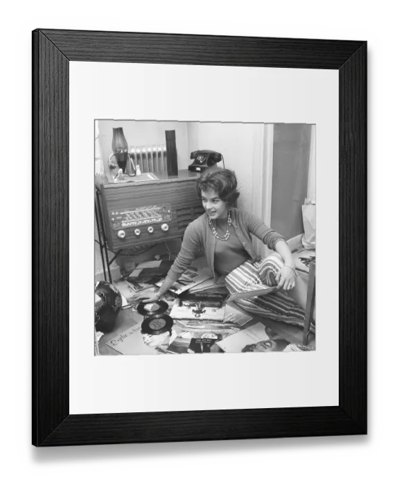 Framed Print : Radio listeners in the past. A woman is seen on the floor with records by popular singers and groups of the 1950s Framed Print : Radio listeners in the past. A woman is seen on the floor with records by popular singers and groups of the 1950s
