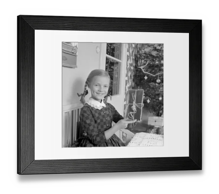 Framed Print : Christmas in the 1960s. A young girl holds a nice wrapped christmas package. Sweden 1963 Ref 4827