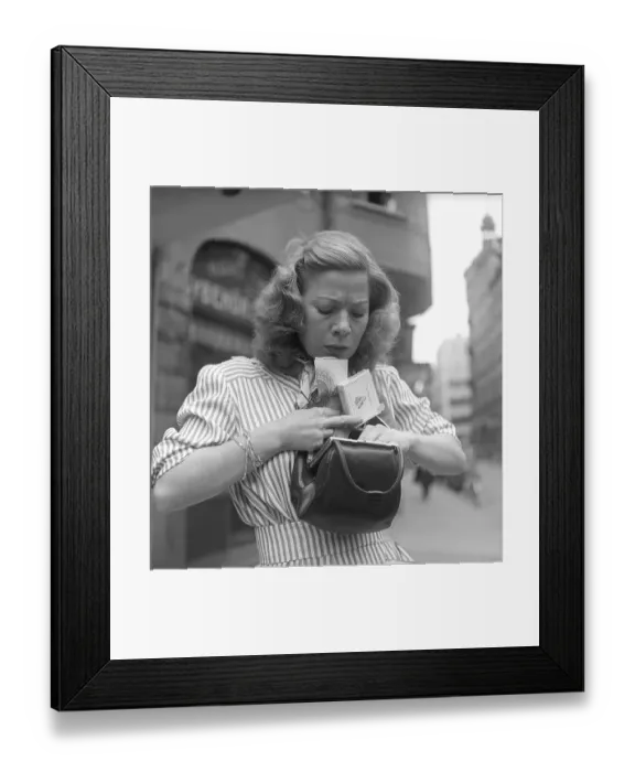 Framed Print : In the 1940s. A woman is seen looking through her purse and tries to find something
