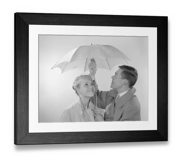 Framed Print : 1960s couple. A happy smiling couple is standing under an umbrella