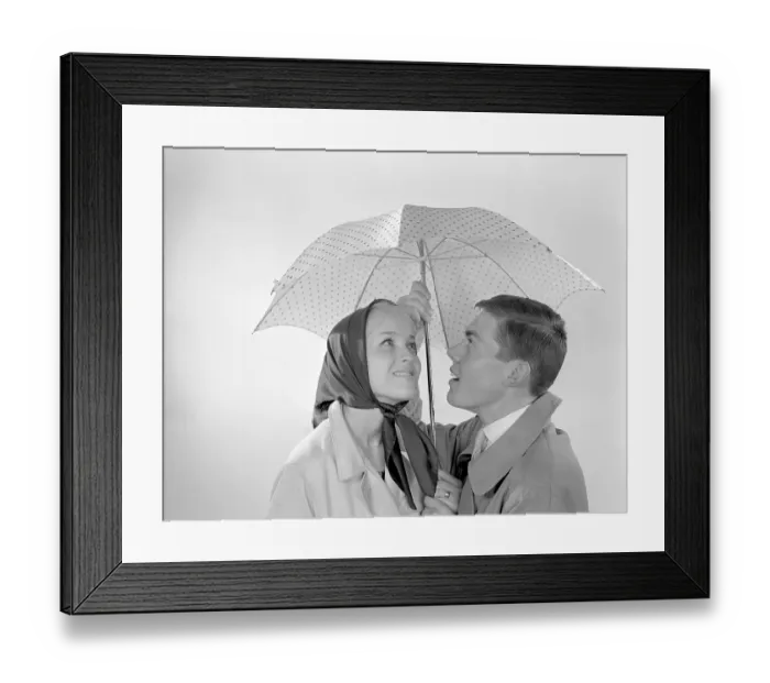 Framed Print : 1960s couple. A happy smiling couple is standing under an umbrella