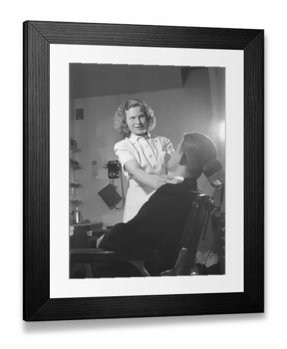 Framed Print : Getting a shave in the 1940s. A young woman in a barber shop