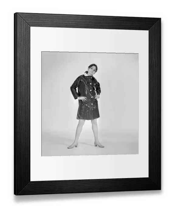 Framed Print : 1960s woman in raincoat. A young woman dressed in a raincoat of plastic material