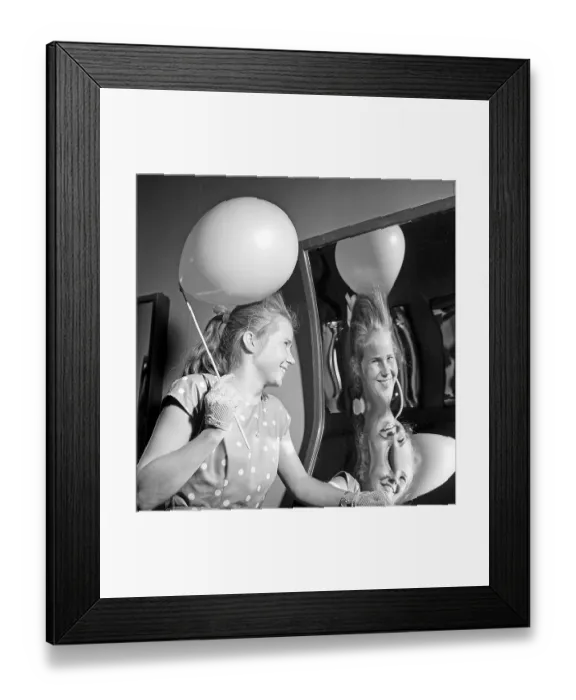 Framed Print : Amusement park in the 1950s. A teenage girl is laughing at how she look in a funny mirror