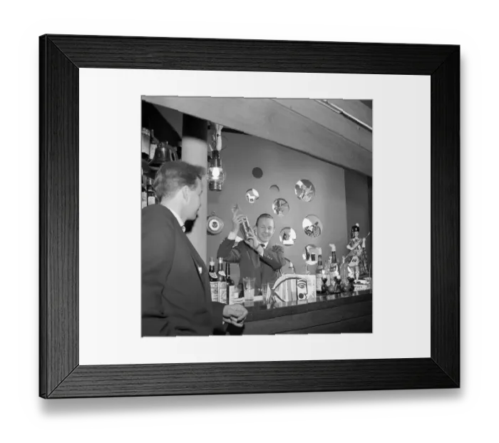 Framed Print : Bar in the 1950s. A bartender is mixing drinks behind the bar counter
