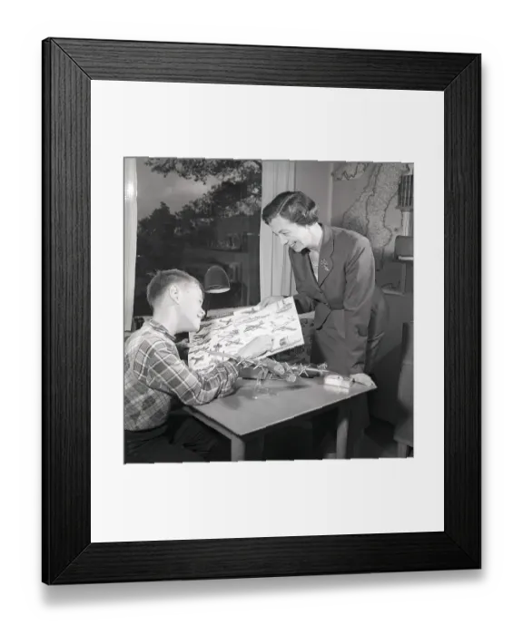 Framed Print : Hobby in the 1950s. A boy is sitting at a table with a plastic model of an American bomb aircraft B29