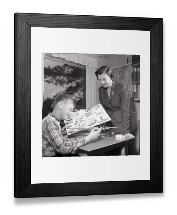 Framed Print : Hobby in the 1950s. A boy is sitting at a table with a plastic model of an American bomb aircraft B29 Framed Print : Hobby in the 1950s. A boy is sitting at a table with a plastic model of an American bomb aircraft B29