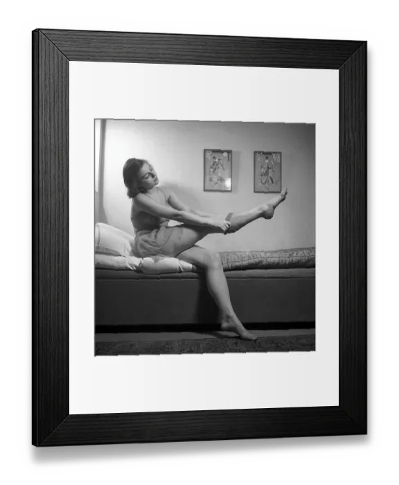 Framed Print : Nylon stockings in the 1940s. A young woman is getting dressed in the moring