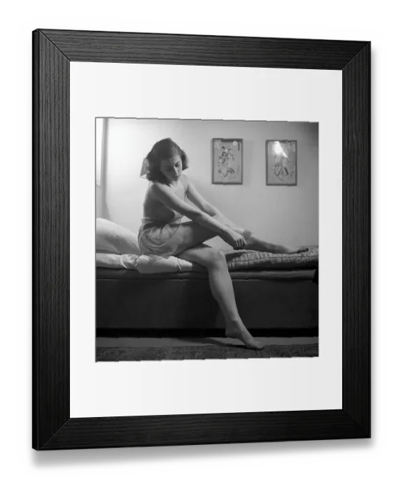 Framed Print : Nylon stockings in the 1940s. A young woman is getting dressed in the moring