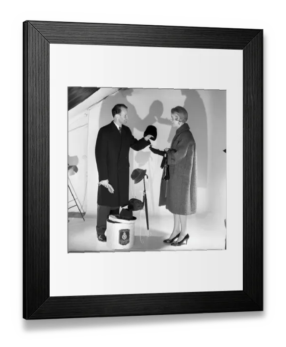 Framed Print : Christys hats London. A couple is photographed in a studio wearing coats