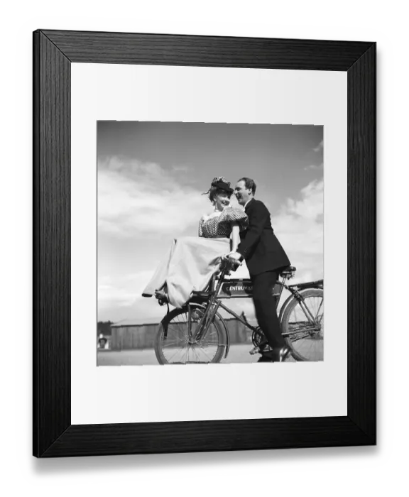 Framed Print : 1940s couple on a bicycle. A young couple is riding their bicycles on a sunny day Framed Print : 1940s couple on a bicycle. A young couple is riding their bicycles on a sunny day