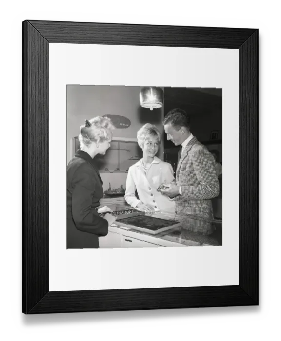 Framed Print : Love in the 1950s. A young couple at a jewelry shop is selecting wedding rings
