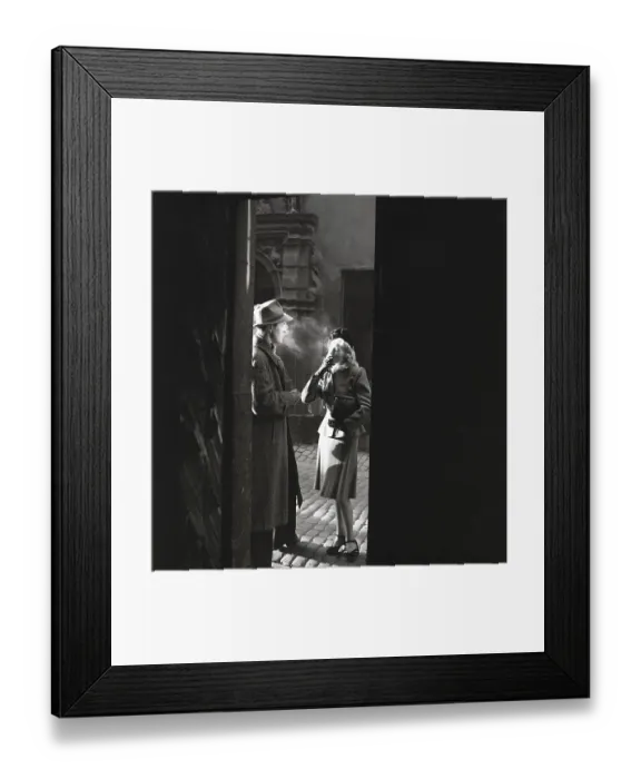 Framed Print : 1940s couple. A couple pictured in the evening sun in an old street smoking a cigarette