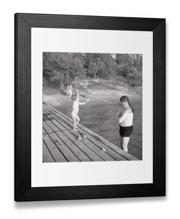 Framed Print : 1940s summer. A man and father is standing caught by his daughter in a fishing net