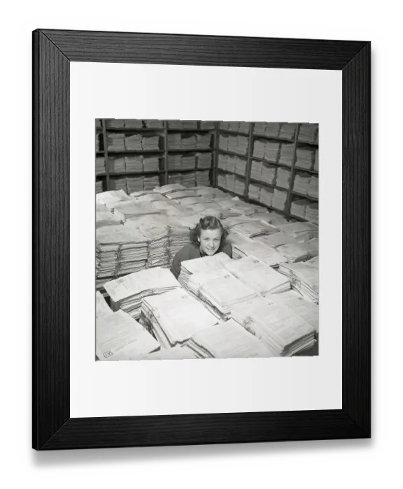 Framed Print : 1940s working girl. A young woman in the storage room of thousands and thousands of documents