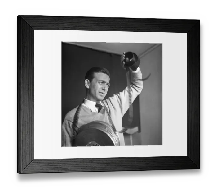 Framed Print : Film interest in the 1950s. A man holding a roll of film is looking at the frames to see what's on it Framed Print : Film interest in the 1950s. A man holding a roll of film is looking at the frames to see what's on it