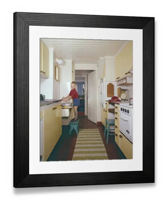 Framed Print : Kitchen of the 50s-60s. A boy is standing on a footstool and washes his hands