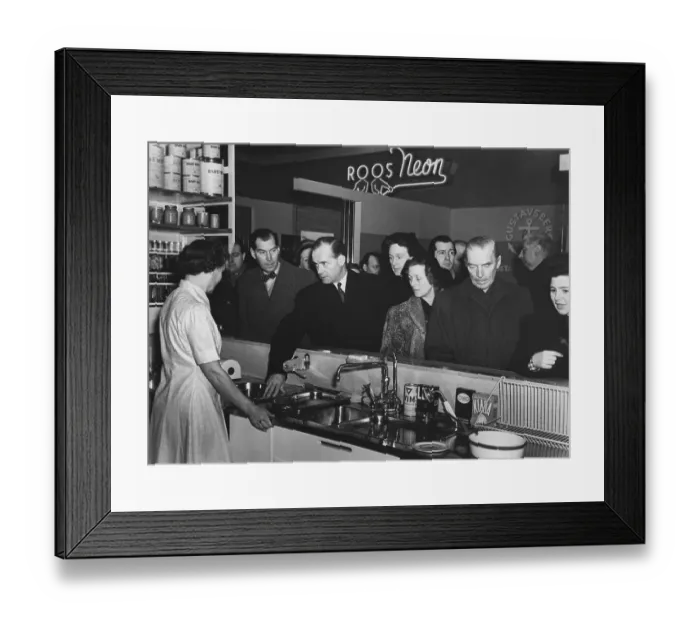 Framed Print : Kitchen of the 1950s. An exhibition at a public consumer fair is going on and visitors at the display of a modern kitchen are interested to know more. A woman in the stand answers questions Framed Print : Kitchen of the 1950s. An exhibition at a public consumer fair is going on and visitors at the display of a modern kitchen are interested to know more. A woman in the stand answers questions