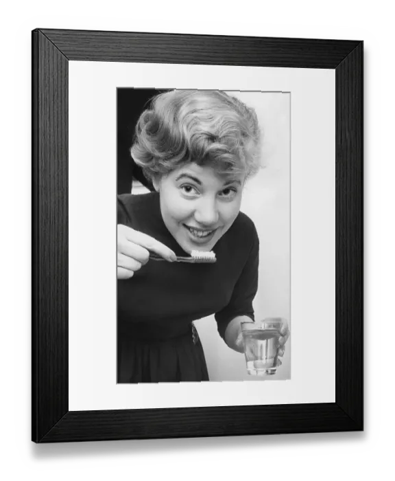 Framed Print : Woman in the 1950s. A young woman is brushing her teath Framed Print : Woman in the 1950s. A young woman is brushing her teath
