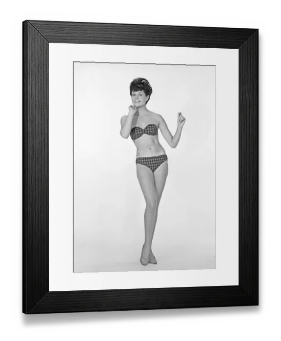 Framed Print : 1960s bikini fashion. A blonde girl in a photographers studio in a typical 1960s bikini