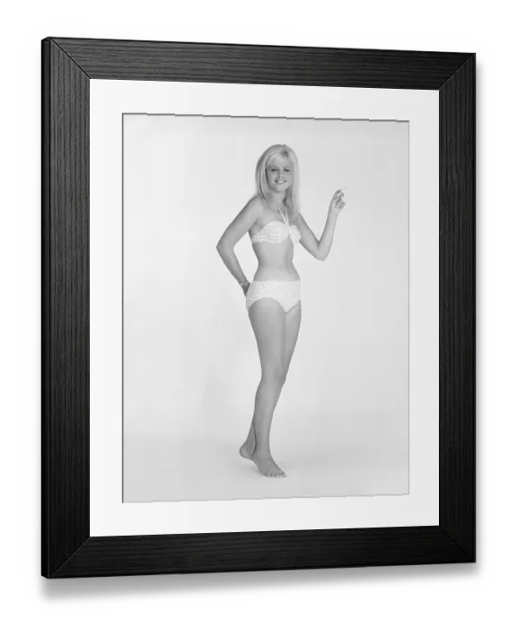 Framed Print : 1960s bikini fashion. A blonde girl in a photographers studio in a typical 1960s bikini