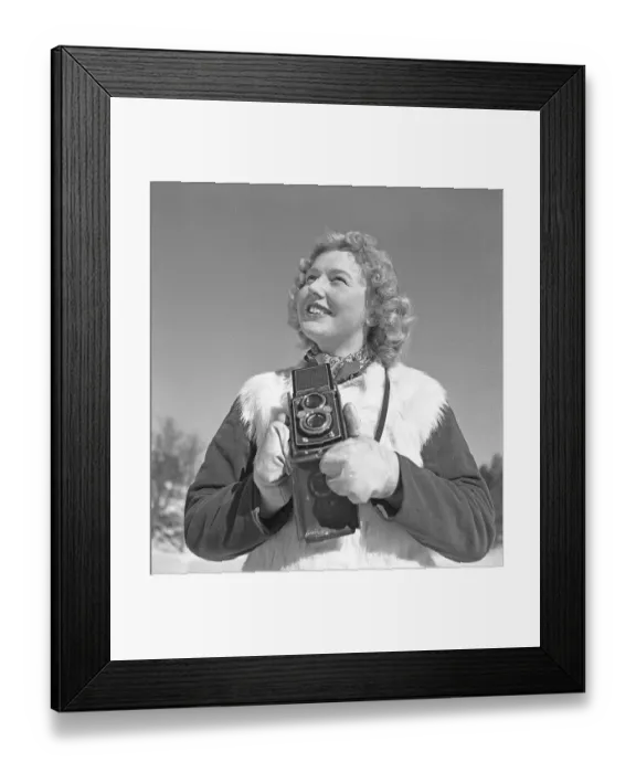 Framed Print : Winter in the 1940s. A young woman is photographing on a winter day Framed Print : Winter in the 1940s. A young woman is photographing on a winter day