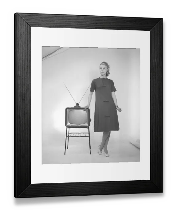 Framed Print : Television in the 1950s. A young woman is standing dressed in a typical 50s dress beside a televison set with an table antenna on top of it. In 1952 1.4 million households in Britain had a television. Photo Kristoffersson ref BZ26. Sweden 1952