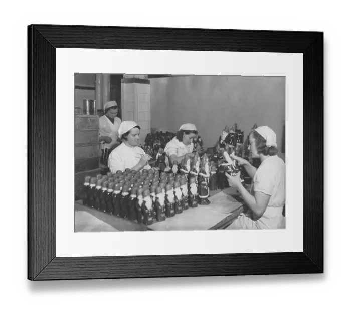 Framed Print : Christmas chokolate. Three young employees in the factory of the swedish chocolate maker company Cloetta. They are busy finishing the chocolate santa clauses that needs to be delivered to the stores