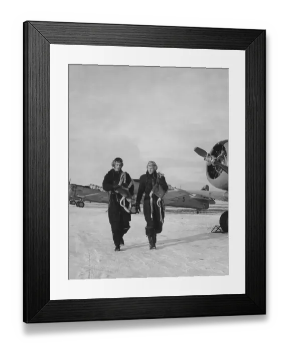 Framed Print : Pilots in the 1950s. Two pilots are walking past fighter aircraft a winter day