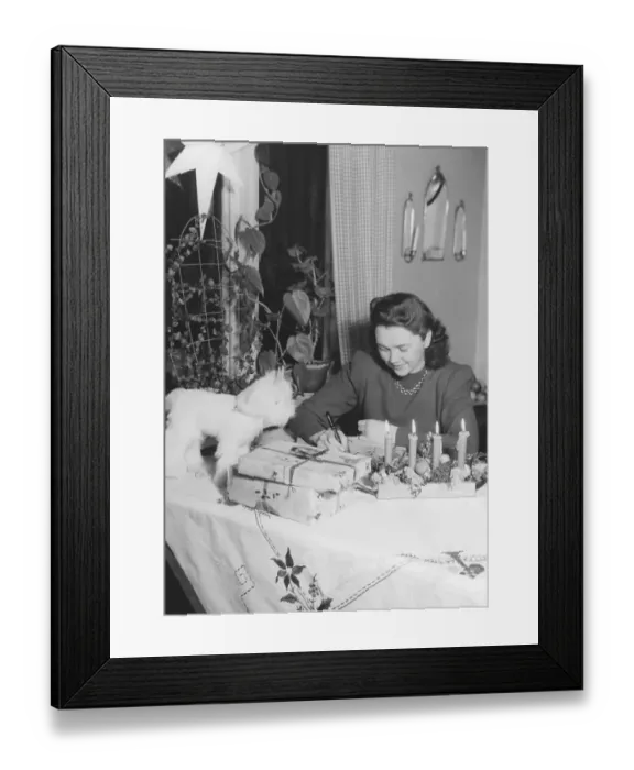 Framed Print : Christmas in the 1940s. A woman is wrapping christmas gifts