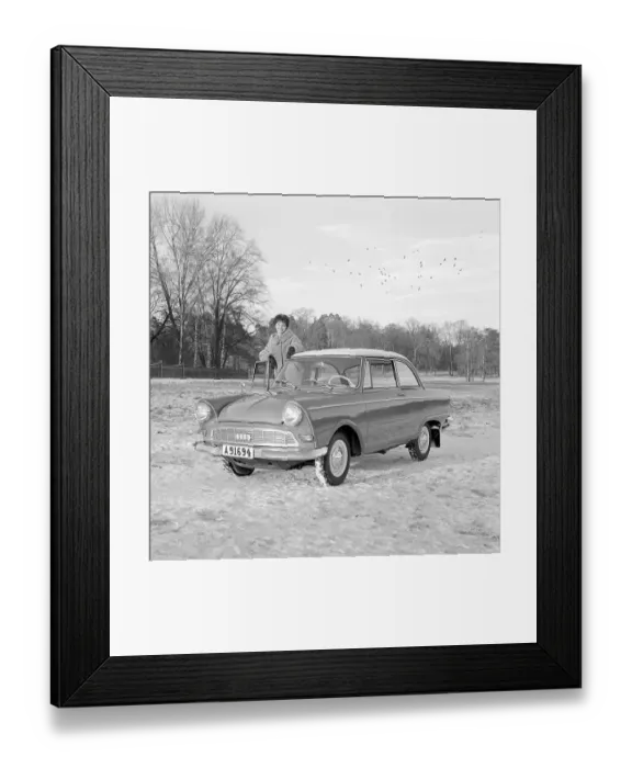 Framed Print : In the 1960s. A young woman in the winter with her brand new car