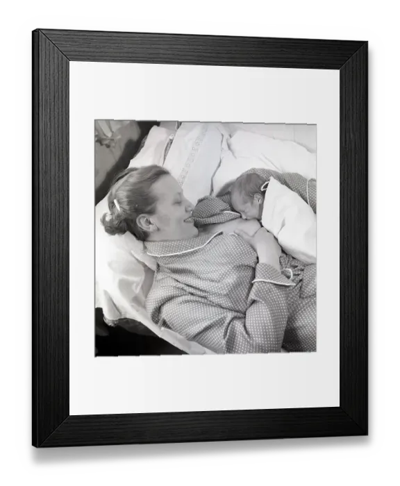Framed Print : 1950s mother nursing her baby. A young woman breastfeeding her baby while lying in bed at home. Sweden 1951 Neg CV / 24 Framed Print : 1950s mother nursing her baby. A young woman breastfeeding her baby while lying in bed at home. Sweden 1951 Neg CV / 24