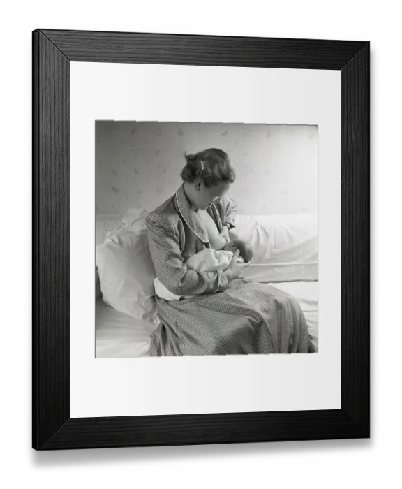 Framed Print : 1950s mother nursing her baby. A young woman breastfeeding her baby at home
