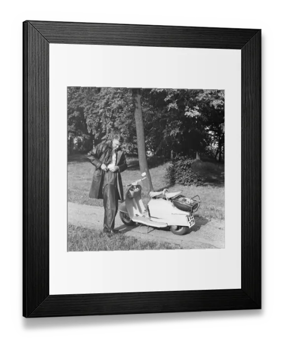 Framed Print : Rain in the 1950s. A young man prepares for a tour on his scooter motorcycle NSU Prima