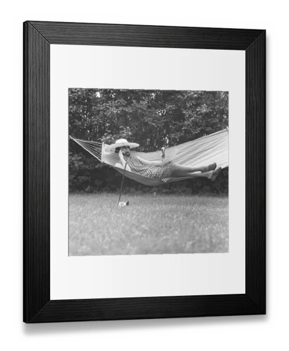 Framed Print : Summer in the 1960s. A lady is lying comfortably in a hammock talking on the phone. Sweden 1961