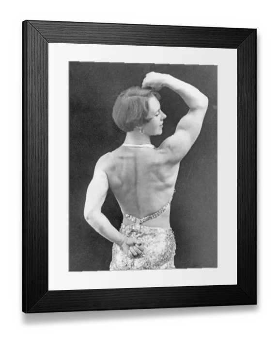 Framed Print : In the 1930s. A woman pictured from behind when she demonstrates her fit body and muscles. A bit of a stage costume is visible